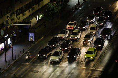 Bucharest, Romania - July 30, 2022: Cars wait at a red traffic light at night on Magheru boulevard...