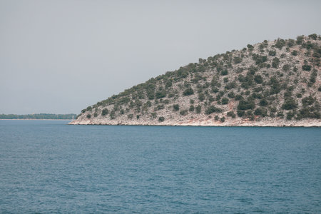 Small Greek island covered with small vegetation during a sunny summer day.の写真素材