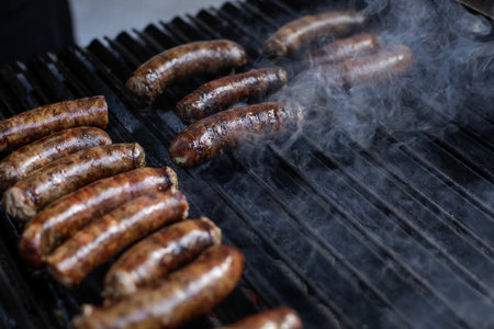 Shallow depth of field (selective focus) details with pork sausages cooking on a barbecue grill, in a European farmers market.の写真素材