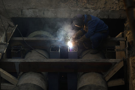 Details with a professional welder welding an industrial metallic pipeline.