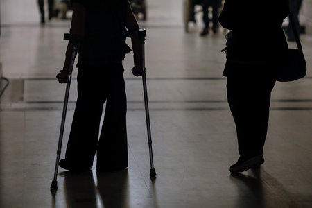 Shallow depth of field (selective focus) silhouette of a woman using crutches.の写真素材