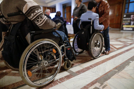Shallow depth of field (selective focus) details with a man in a wheelchair during a convention.の写真素材