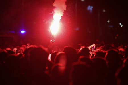 Details with the hands of a man holding a torch inside during a football (soccer) game.