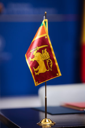 Sri Lankan flag on a golden small pole on a wooden table during a diplomatic eventの写真素材