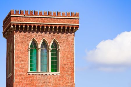 ancient red brick tower with colorful trifora windows against a blue skyの写真素材