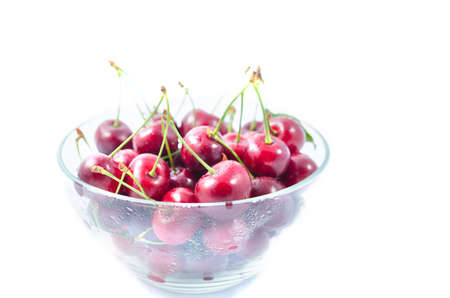 Heap of sweet cherries in a glass bowl isolated on white