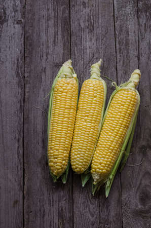 corn cob and green leaves on wooden background, foodの写真素材