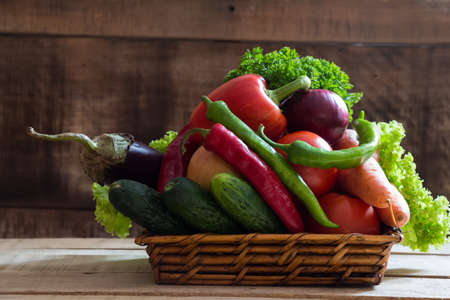 Fresh vegetables in basket on  wooden tableの写真素材