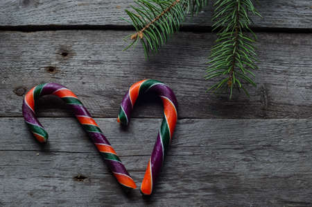 Three colourfull candy canes on a wooden background.