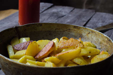 Fresh appetizing roasted potato chips in a metal frying pan close-up, in bright sunlightの写真素材