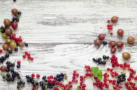 black and red currants gooseberries on wooden backgroundの写真素材