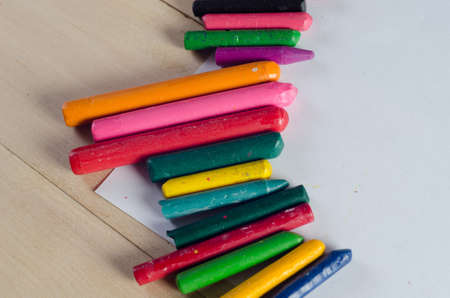 Wax crayons on white sheet, wooden backgroundの写真素材