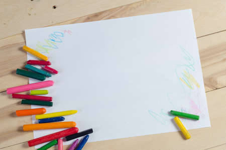 Wax crayons on white sheet, wooden backgroundの写真素材