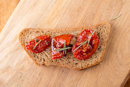 Sandwich with goat cheese, sun-dried tomatoes and thyme, served on the Board at a bright wooden...