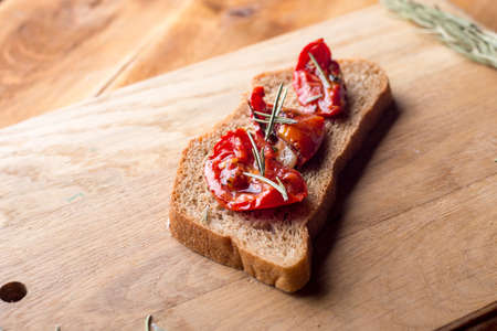Sandwich with goat cheese, sun-dried tomatoes and thyme, served on the Board at a bright wooden...
