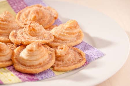 Homemade puff pastry cookies with sugar on a white plate