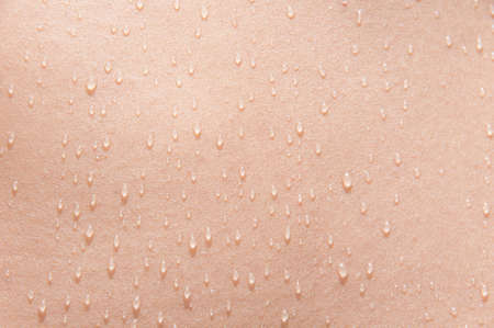 Water drops on the skin of a young woman in the sunの写真素材