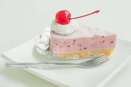 A sliced of cherry cream cake on white plate and backgroundの写真素材