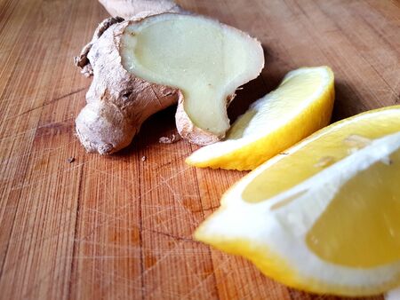 yellow bright sliced lemon and ginger on a  wooden surfaceの写真素材