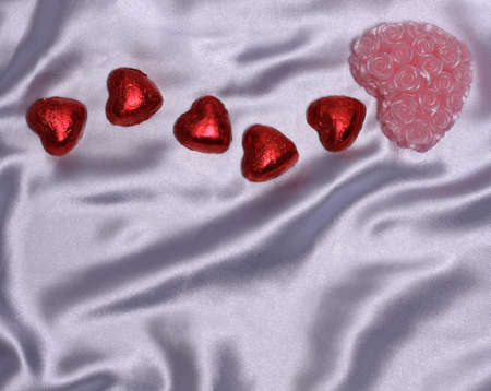 Heart-shaped candies and candle on blue satinの写真素材