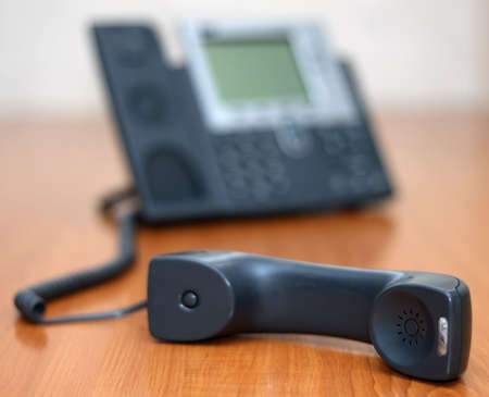 Phone receiver lying on a tableの写真素材