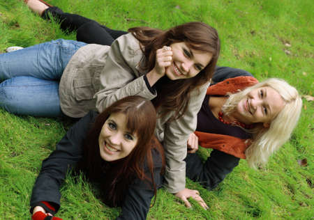 Company of girls having fun on green grassの写真素材