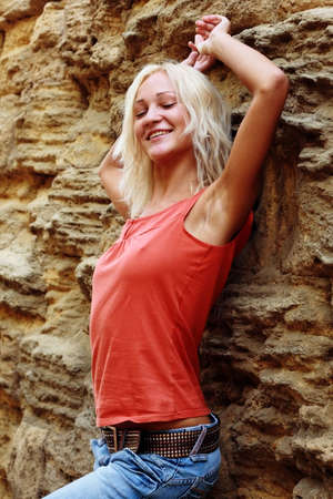 Beautiful girl posing on a stone wall backgroundの写真素材