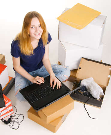 Young beautisul woman surrounded by delivered orders, surfing an online store at her laptopの写真素材