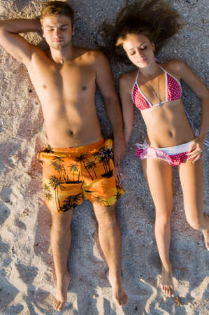 Young beautiful couple sunbathing on the sandy beachの写真素材