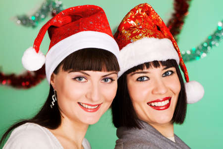Cheerful girls in christmas hats on festive backgroundの写真素材