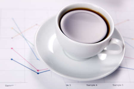 Cup of strong coffee over business diagrams, closeup soft focus photoの写真素材
