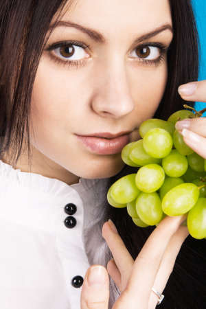 Beautiful young lady holding grapes, face portraitの写真素材