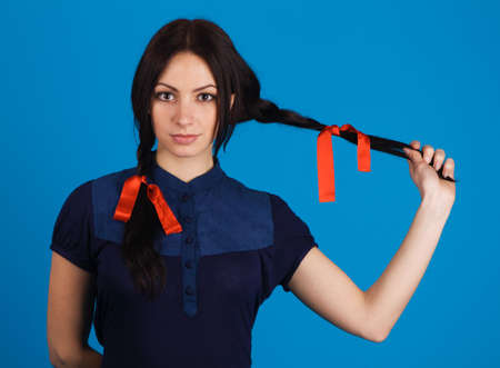 Beautiful brunette with red ribbons on braids, blue backgroundの写真素材