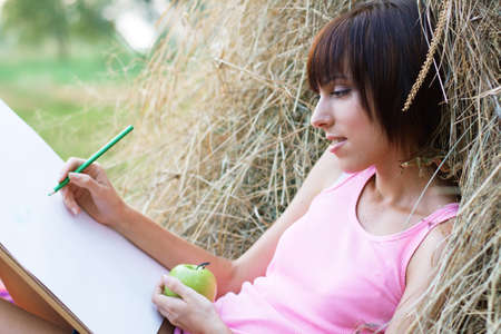 Lovely girl having rest and drawing in the parkの写真素材