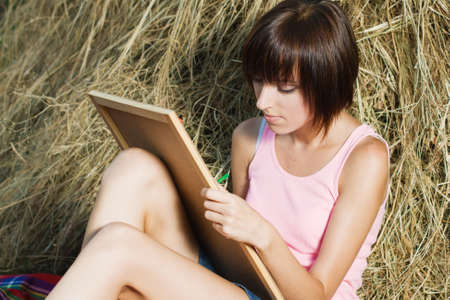 Lovely girl having rest and drawing in the parkの写真素材