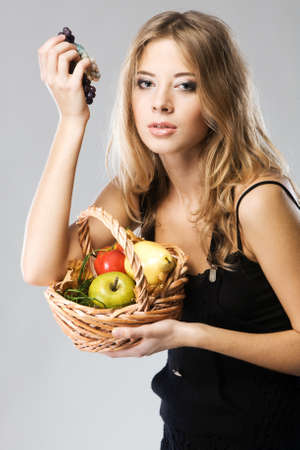 Portrait of a pretty woman with a basket of ripe fruitの写真素材