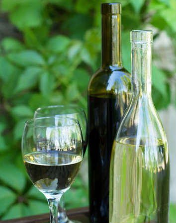 Bottles of red and white wine with grapes, in natural lightの写真素材