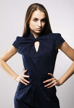 Beautiful fashion model in strict blue dress, gray background