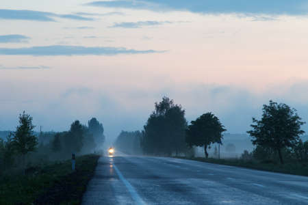 Misty rural road with a motorcyle driving alongの写真素材