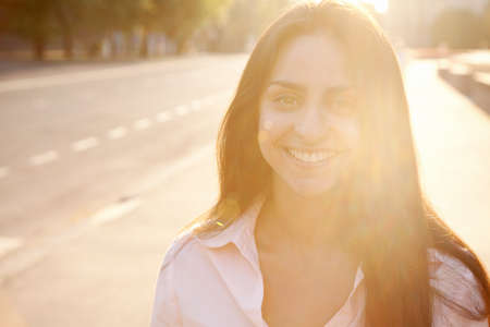 Beautiful lady in sunset light walking along the street