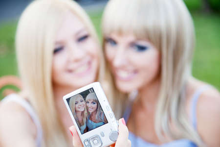 Two beautiful young girl friends with a digital photo cameraの写真素材