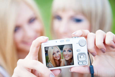 Two beautiful young girl friends with a digital photo cameraの写真素材