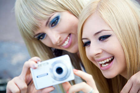 Two beautiful young girl friends with a digital cameraの写真素材