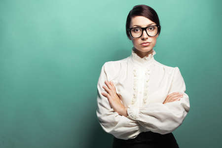 Strict woman in large glasses, green background