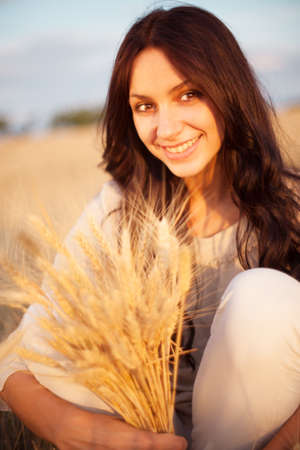 Beautiful brunette lady in wheat field at sunsetの写真素材