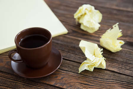 Notepad on a wooden table with crumpled sheets aroundの写真素材