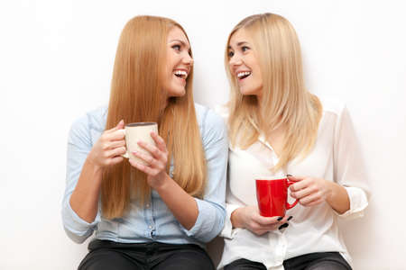 Two female friends drinking coffee and chattingの写真素材