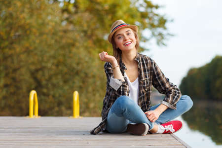 Young beautiful girl sitting on a pierの写真素材