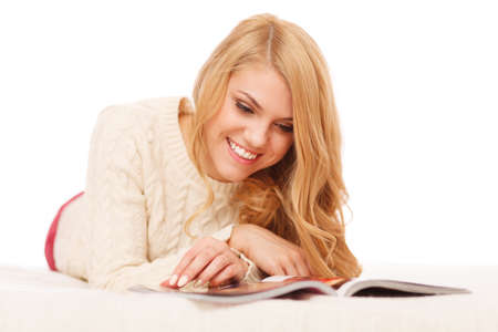 Young beautiful woman reading a magazine in bed