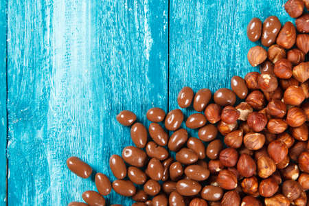 Hazelnuts and chocolate sweets on blue wood background